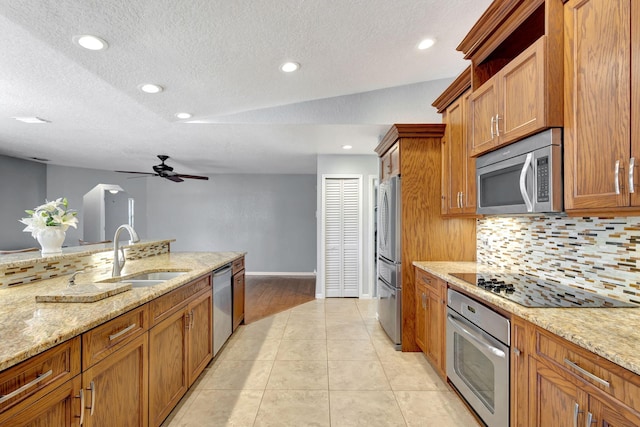 kitchen with sink, vaulted ceiling, ceiling fan, light tile patterned floors, and stainless steel appliances