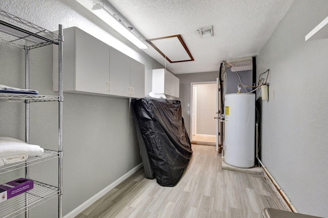 interior space with a textured ceiling, light wood-type flooring, and water heater