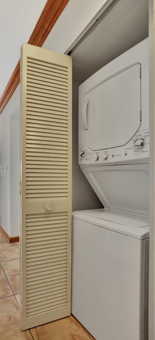 washroom featuring light tile patterned flooring and stacked washer / dryer