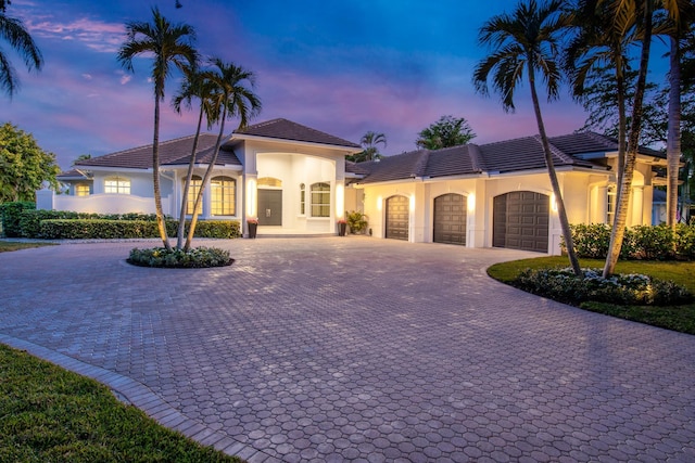 mediterranean / spanish house with a garage, curved driveway, and stucco siding