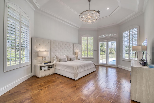 bedroom featuring hardwood / wood-style floors, access to outside, a raised ceiling, and a notable chandelier