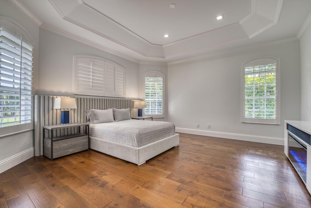 bedroom with a raised ceiling, wood-type flooring, and ornamental molding