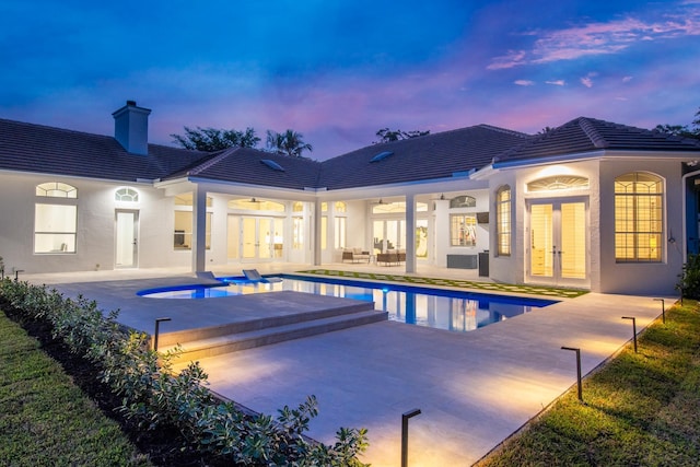 pool at dusk with french doors, a hot tub, ceiling fan, and a patio area