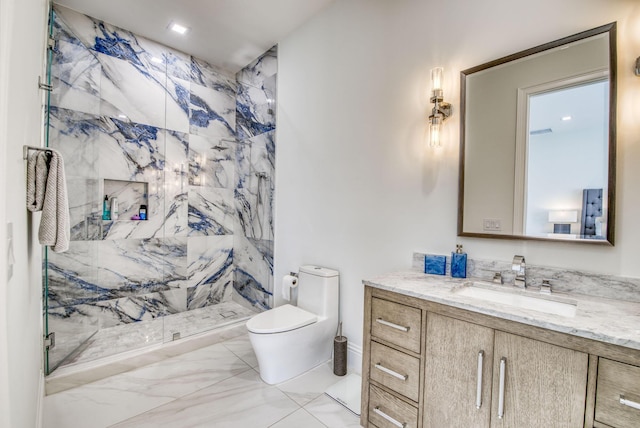 bathroom with a tile shower, vanity, and toilet