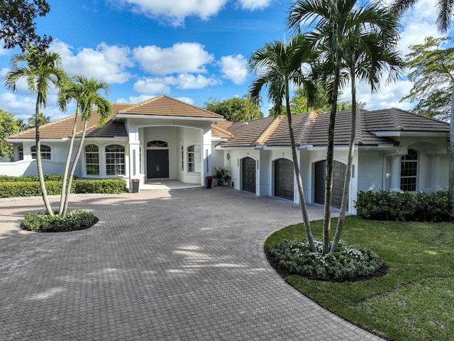 mediterranean / spanish home featuring a garage and a front lawn