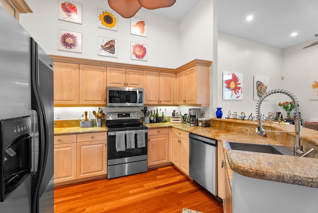 kitchen featuring light brown cabinetry, light wood-type flooring, stainless steel appliances, and sink