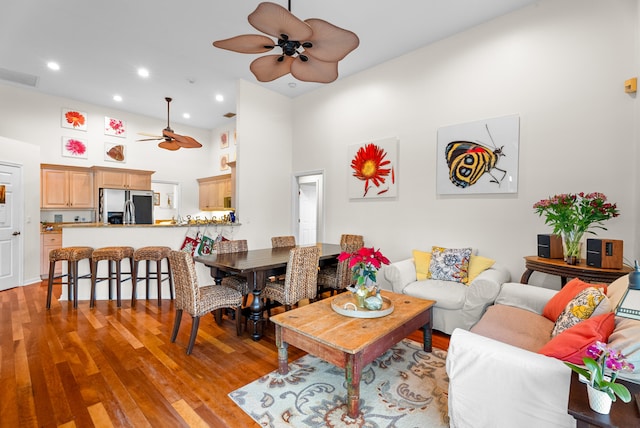 living room featuring a towering ceiling, light hardwood / wood-style floors, and ceiling fan