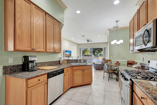 kitchen with ceiling fan with notable chandelier, light tile patterned floors, ornamental molding, appliances with stainless steel finishes, and decorative light fixtures