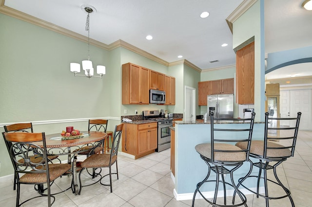 kitchen with crown molding, light tile patterned flooring, stainless steel appliances, and decorative light fixtures