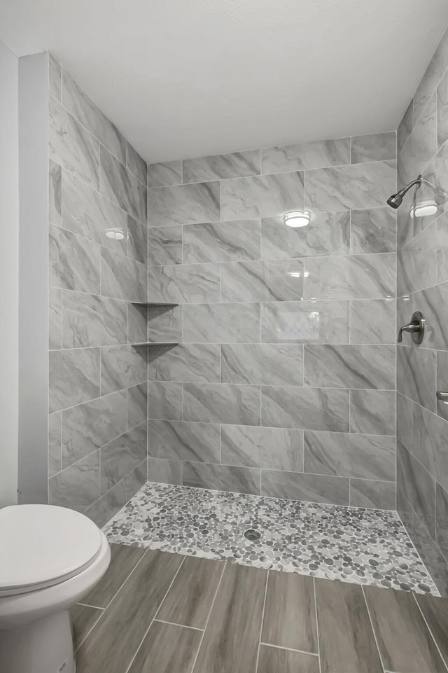 bathroom featuring tiled shower and toilet