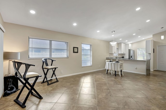 kitchen with hanging light fixtures, white cabinets, stainless steel refrigerator, a kitchen bar, and kitchen peninsula