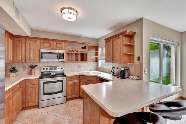 kitchen with open shelves, appliances with stainless steel finishes, a sink, a peninsula, and a kitchen bar