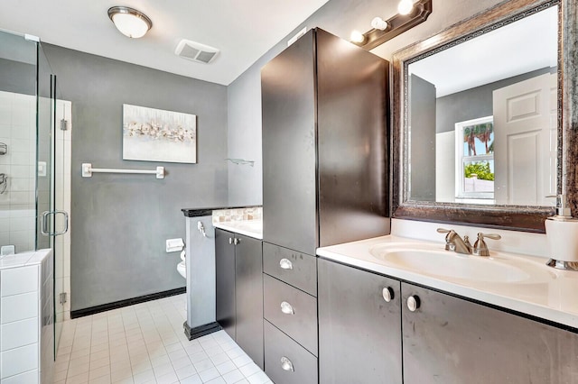 bathroom with tile patterned flooring, toilet, vanity, and a shower with shower door