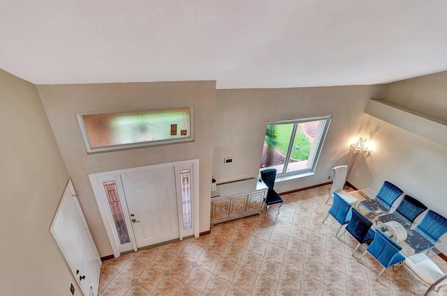 entrance foyer featuring vaulted ceiling, light tile patterned floors, and baseboards