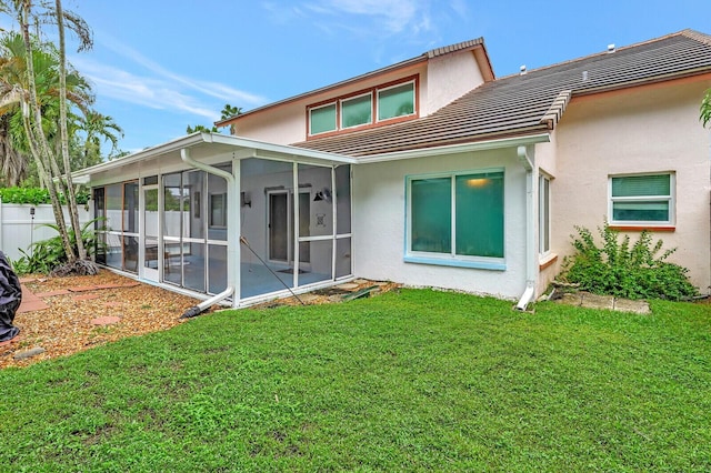 rear view of house featuring a sunroom and a yard