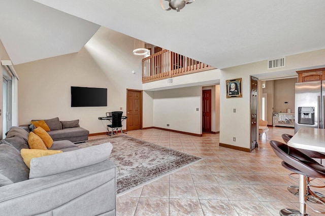 living area with light tile patterned floors, high vaulted ceiling, visible vents, and baseboards