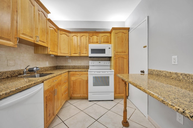 kitchen with backsplash, light stone counters, white appliances, sink, and light tile patterned floors