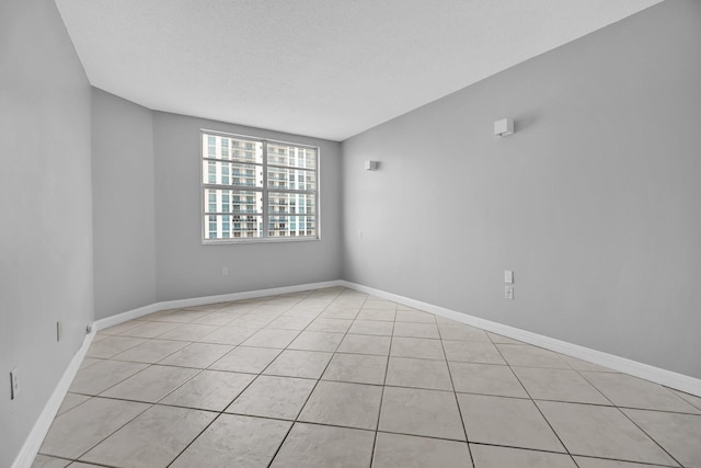 unfurnished room featuring vaulted ceiling, light tile patterned flooring, and a textured ceiling