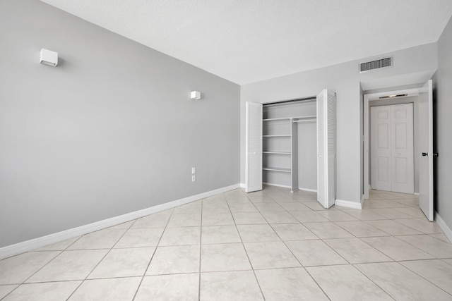 unfurnished bedroom with light tile patterned flooring, a textured ceiling, and a closet