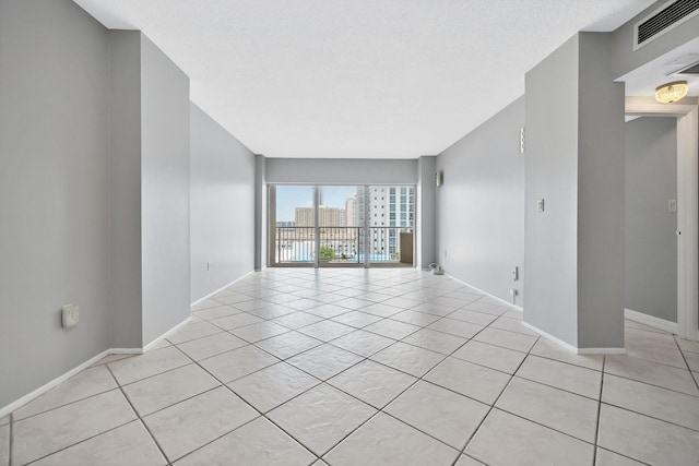 spare room with light tile patterned floors and a textured ceiling