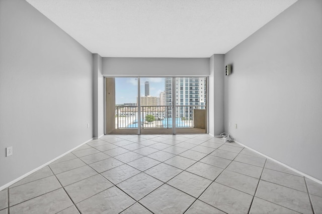 unfurnished room featuring light tile patterned flooring and a textured ceiling