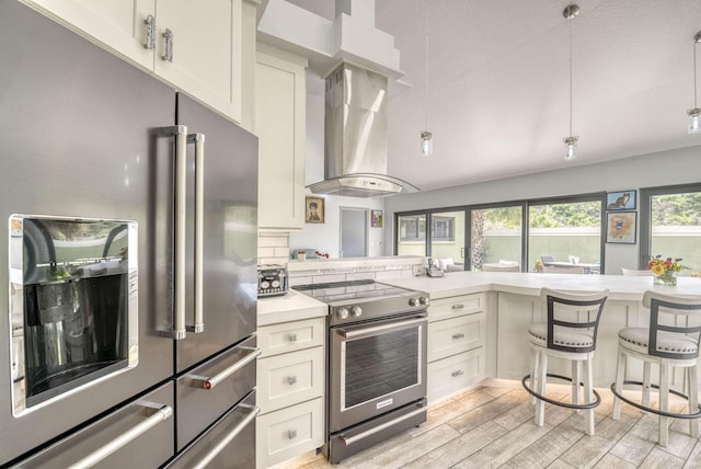 kitchen with a breakfast bar, light wood-type flooring, appliances with stainless steel finishes, island range hood, and kitchen peninsula