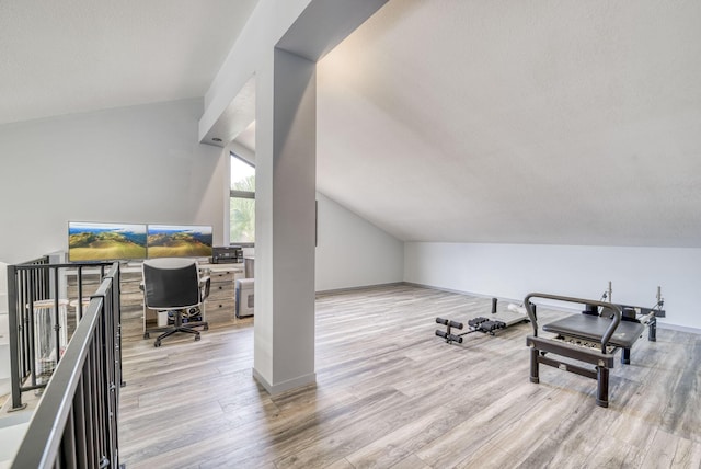 workout room with light hardwood / wood-style flooring and vaulted ceiling