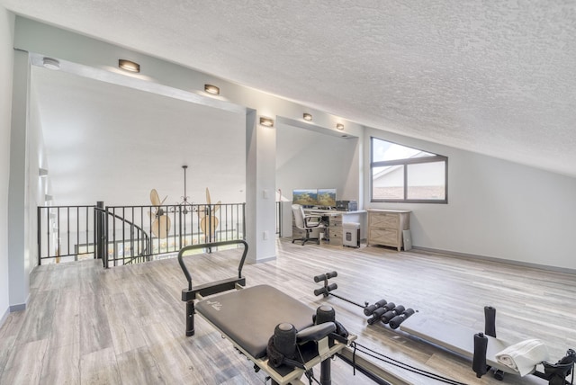 workout room with hardwood / wood-style flooring, lofted ceiling, and a textured ceiling