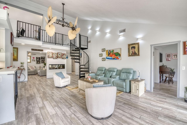 living room featuring light wood-type flooring, an inviting chandelier, and high vaulted ceiling