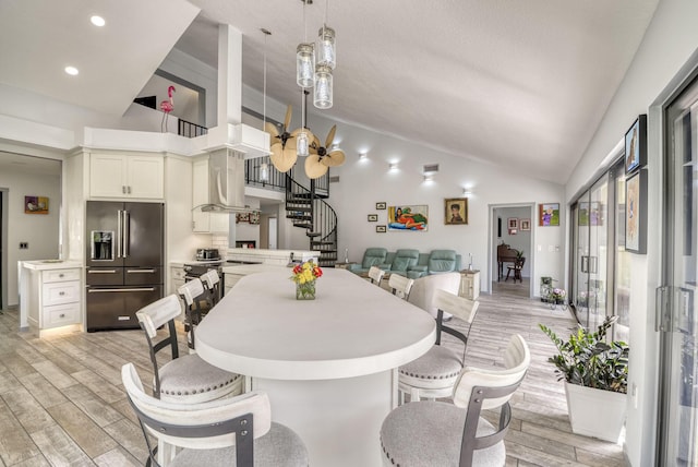 dining space with high vaulted ceiling and light hardwood / wood-style floors