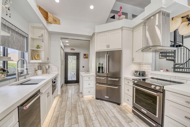 kitchen featuring ventilation hood, white cabinets, sink, and appliances with stainless steel finishes