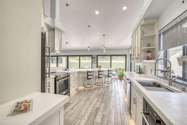 kitchen featuring sink, ventilation hood, appliances with stainless steel finishes, white cabinets, and light wood-type flooring