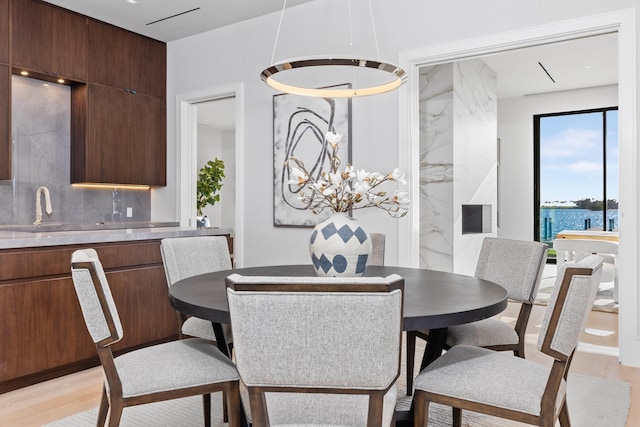 dining area featuring a chandelier, light wood-type flooring, and a water view