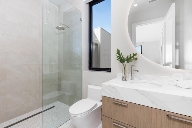 bathroom featuring vanity, toilet, and a tile shower