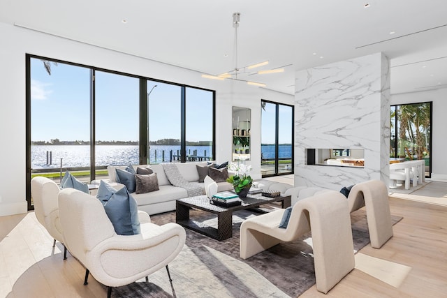 living room featuring a water view, light hardwood / wood-style floors, and an inviting chandelier