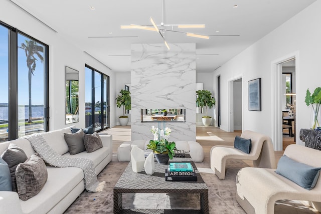 living room with light wood-type flooring, a water view, and an inviting chandelier