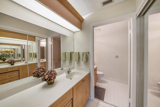 bathroom featuring tile patterned flooring, a textured ceiling, vanity, and toilet