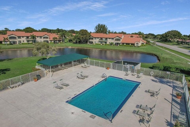 view of pool with a patio, a water view, and a lawn