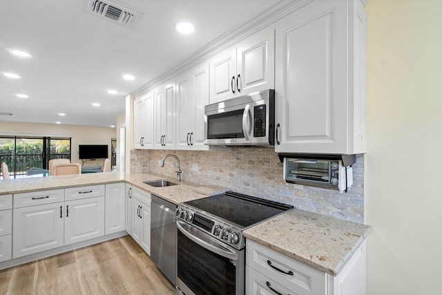 kitchen featuring decorative backsplash, light wood-type flooring, white cabinetry, and stainless steel appliances