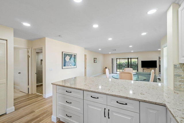 kitchen featuring white cabinetry, light stone counters, and light wood-type flooring