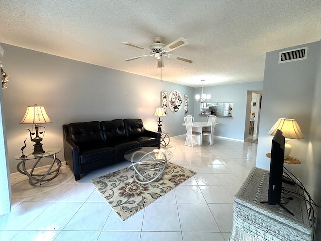 tiled living room featuring ceiling fan with notable chandelier and a textured ceiling