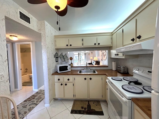 kitchen featuring white appliances, cream cabinets, sink, ceiling fan, and light tile patterned floors