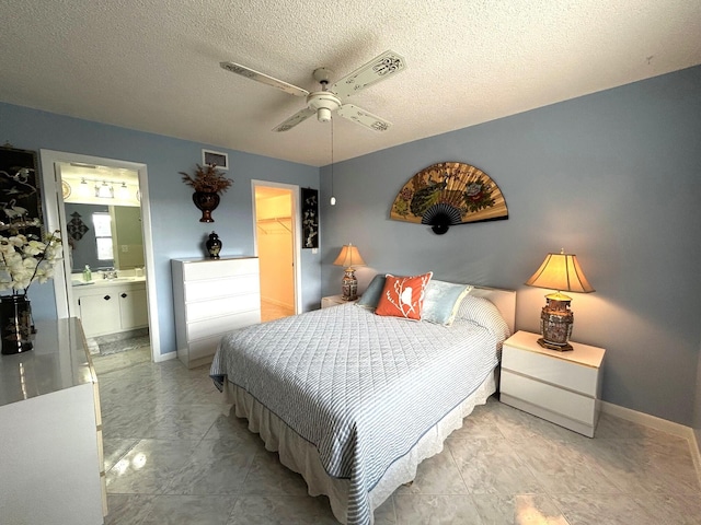 bedroom with ensuite bathroom, ceiling fan, a spacious closet, a textured ceiling, and a closet