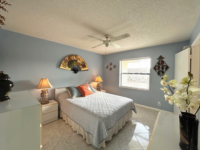 bedroom with ceiling fan, light tile patterned floors, and a textured ceiling