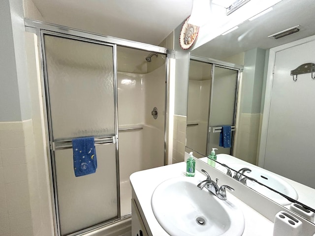 bathroom featuring a shower with door and vanity