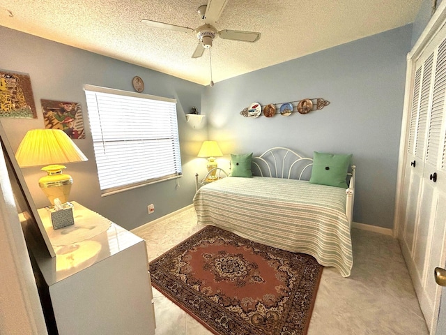 bedroom featuring ceiling fan, a textured ceiling, light carpet, and a closet