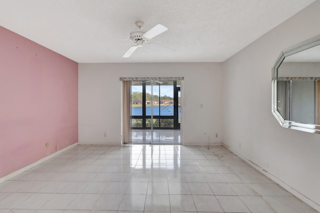 spare room with light tile patterned floors, a textured ceiling, a water view, and ceiling fan