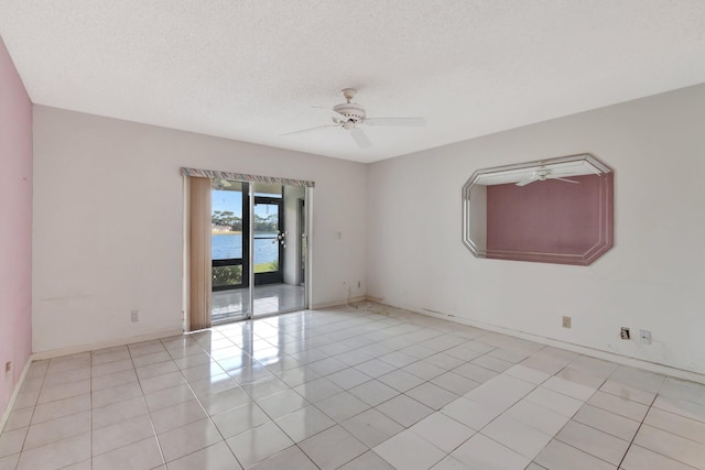 tiled empty room with ceiling fan, a water view, and a textured ceiling