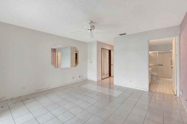 unfurnished room with ceiling fan, light tile patterned floors, and a textured ceiling