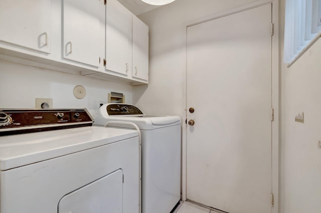 washroom featuring separate washer and dryer, light tile patterned floors, and cabinets